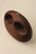 Close-up angled view of the walnut wood handbag, showing its smooth sculptural form, oval openings, and silver-tone hardware.