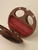 Open walnut wood handbag revealing its red leather-lined interior, with two oval openings in the wooden frame and silver-tone hardware.