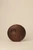 Closed, circular dark walnut wood handbag with two subtle crescent-shaped indentations, photographed against a neutral background.