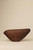 Closed dark walnut wood Bird handbag with a sleek, elongated form and gently curved silhouette.