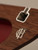 Close-up of the interior of the bag showing the Frick Collection monogram and silver-tone hardware against the walnut wood.