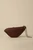 Walnut wood Bird handbag with a sleek, elongated form and gently curved silhouette, shown closed with the silver-tone wristlet chain attached and draped beside it.