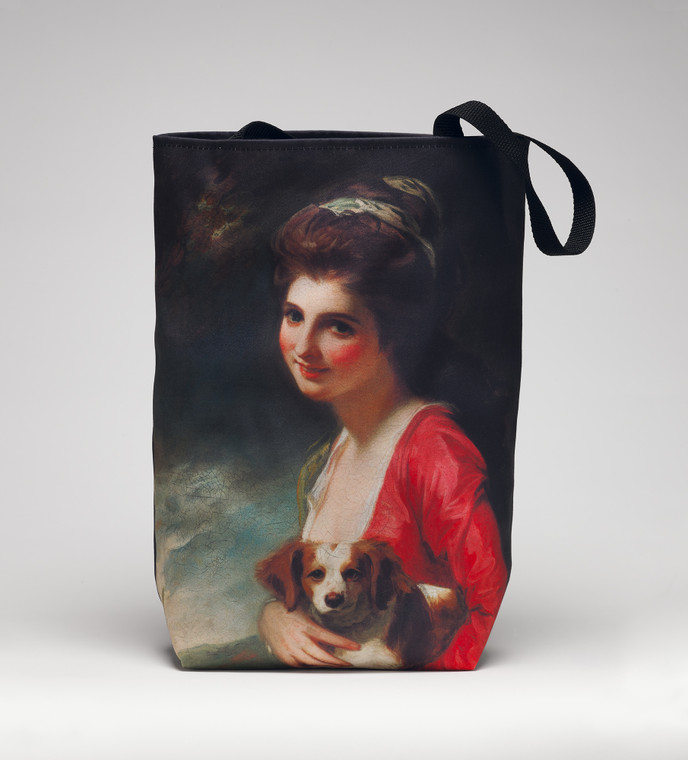 Tote standing on a white surface with a print of a white woman in a red and white dress holding a puppy.