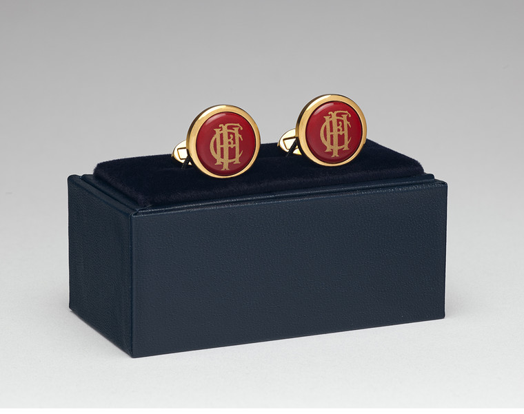 Gold and burgundy cufflinks atop a blue case