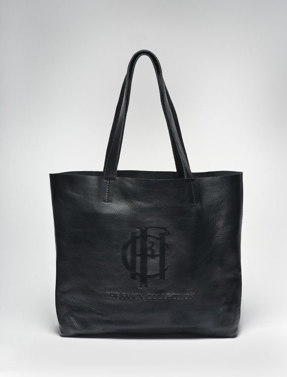 Leather black tote with the words The Frick Collection and its logo on its side and straps standing upright forming a triangle