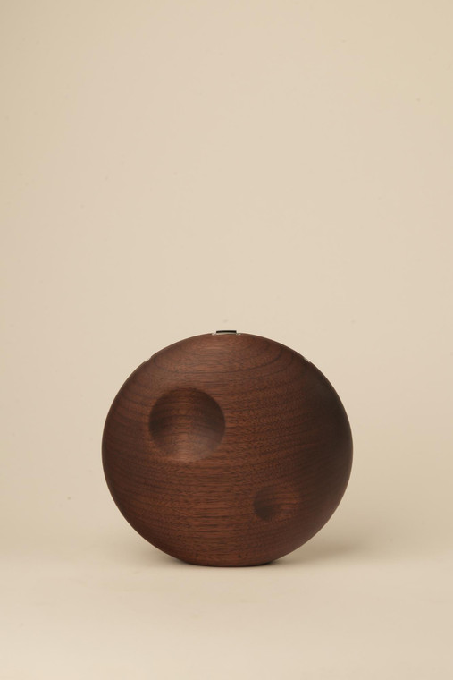 Closed, circular dark walnut wood handbag with two subtle crescent-shaped indentations, photographed against a neutral background.