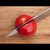 Demonstrating the razor-sharp edge of an authentic Aritsugu Japanese knife by effortlessly slicing a ripe tomato.