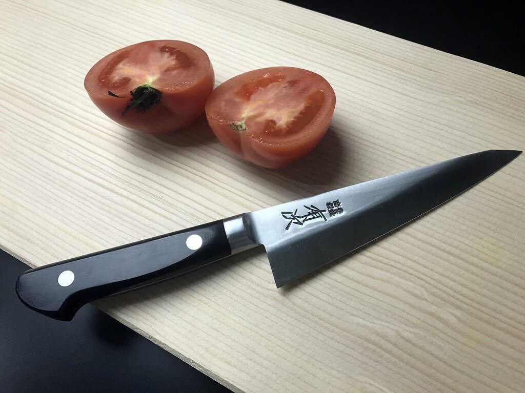 Demonstrating the razor-sharp edge of an Aritsugu chef knife by effortlessly slicing a tomato.