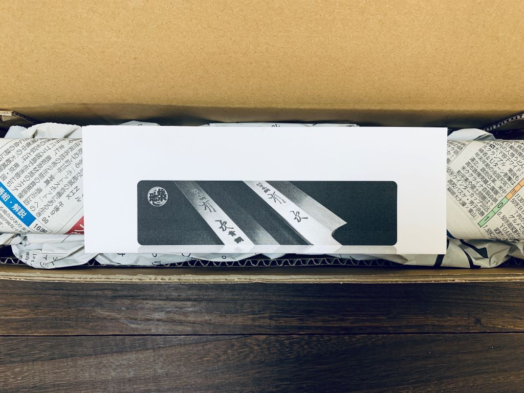 Professional secure packaging of an authentic Tsukiji Aritsugu knife with traditional Japanese wrapping and newspaper padding for safe worldwide shipping.