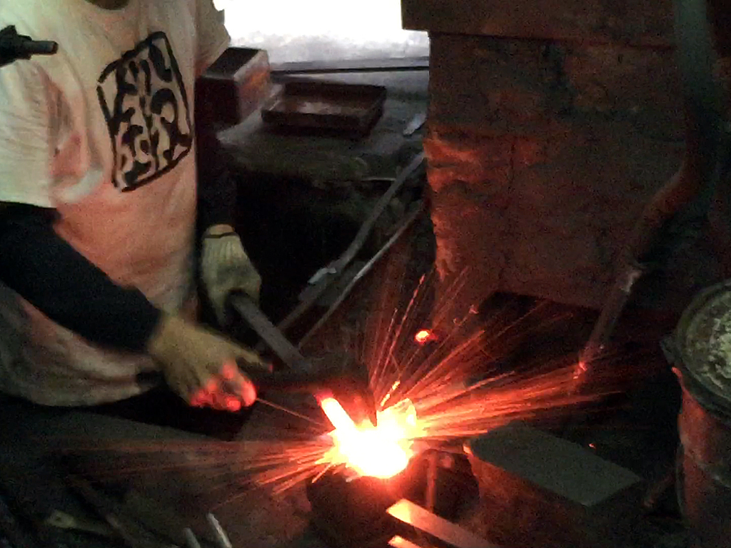 Traditional Japanese blacksmith forging a high-carbon steel knife using centuries-old swordsmith techniques.