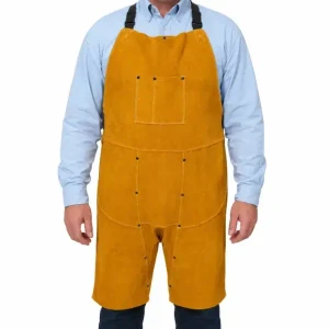 Worker wearing a golden leather welding apron with adjustable shoulder straps, utility pockets, and split-leg coverage for welding and metalworking tasks.