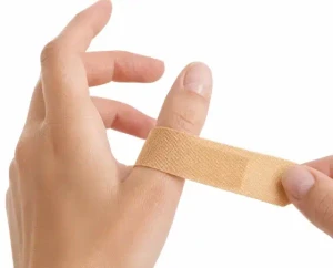 Hand applying adhesive bandage around finger for minor cut protection