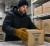 Cold storage worker wearing insulated freezer gloves while handling Keep Frozen boxes in a walk-in freezer warehouse.