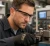 Machine shop worker wearing MCR Safety Storm clear wraparound safety glasses while inspecting precision equipment in an industrial workshop.