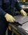 Worker wearing yellow knit Kevlar gloves while handling sharp-edged metal sheets in an industrial metalworking shop