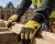 Construction worker wearing yellow and black work gloves while gripping lumber at an outdoor framing