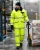 Worker wearing yellow hi-vis insulated cold-weather coveralls handling product with pallet jack