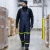 Cold storage worker wearing reflective insulated freezer bib pants, beanie, gloves, and work boots while walking through a freezer warehouse
