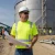 Site supervisor wearing a hi-vis safety shirt while reviewing blueprints at a large water tank construction site