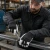 Industrial worker wearing insulated goatskin leather palm gloves while tightening hardware on a metal frame in a workshop