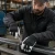 Industrial worker wearing insulated goatskin leather palm gloves while tightening hardware on a metal frame in a workshop