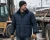 Worker wearing a navy insulated work jacket, beanie, gloves, and cold-weather PPE