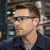 Industrial worker wearing clear lens safety glasses with a black frame while working in a manufacturing facility.