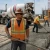 Construction workers wearing orange hi-vis reflective safety vests and rubber boots during a concrete pour near a cement mixing truck