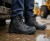 Worker wearing black waterproof safety boots on a wet construction site with heavy equipment