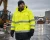 Worker wearing an ANSI Class 3 hi-vis winter parka during snowy roadwork in wet cold weather.
