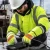 Worker wearing hi-vis insulated freezer gloves, hard hat, safety glasses, and cold-weather PPE while handling cable at an outdoor winter industrial site.
