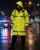Officer wearing a long ANSI compliant tactical raincoat during rainy night duty on a closed city street.