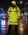 Officer wearing a long ANSI compliant tactical raincoat during rainy night duty on a closed city street.