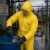 Worker wearing a yellow Tychem C chemical protective suit, safety goggles, and chemical-resistant gloves while handling a drum in a hazardous material area