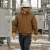 Electrical utility worker wearing an insulated FR hooded jacket, hard hat, safety glasses, and gloves while working near high-voltage substation equipment