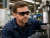 Worker wearing black smoke lens safety glasses while inspecting machinery in an industrial workshop