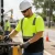 Worker wearing an ANSI Class 2 hi-vis short sleeve safety shirt with black contrast panel during roadside equipment work