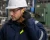 Worker inserting corded foam earplugs while wearing a hard hat and safety glasses in a factory