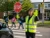 School crossing guard wearing hi-vis gloves and safety vest while holding a stop sign and directing traffic near a school crosswalk.