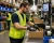 Worker wearing a hi-vis mesh safety vest while packing products on a warehouse pick and pack assembly line.