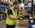 Worker wearing a hi-vis mesh safety vest while packing products on a warehouse pick and pack assembly line.