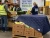 Food bank workers sorting bananas and produce while using a quilted insulated cover to help protect food boxes in a warehouse setting