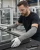 Worker wearing gray cut-resistant sleeves and safety glasses while handling glass and aluminum window frames in a manufacturing shop