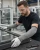 Worker wearing gray cut-resistant sleeves and safety glasses while handling glass and aluminum window frames in a manufacturing shop
