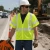 Worker wearing an ANSI Type R Class 3 mesh safety vest during roadwork traffic control