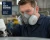 Worker wearing North Defender respirator filters while using spray equipment in an industrial workshop