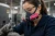 Female industrial worker wearing a half-face respirator with 3M 60921 P100 cartridges while working in a factory environment.