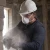 Worker wearing a 3M 8200 N95 respirator disposable dust mask while cutting concrete in a dusty construction environment