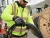 Worker wearing Mechanix FastFit work gloves while rolling fiber cables at an outdoor utility jobsite