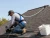 Roofer wearing an OSHA ANSI roofing fall protection kit with 50ft lifeline, full body harness, and roof anchor on a steep roof